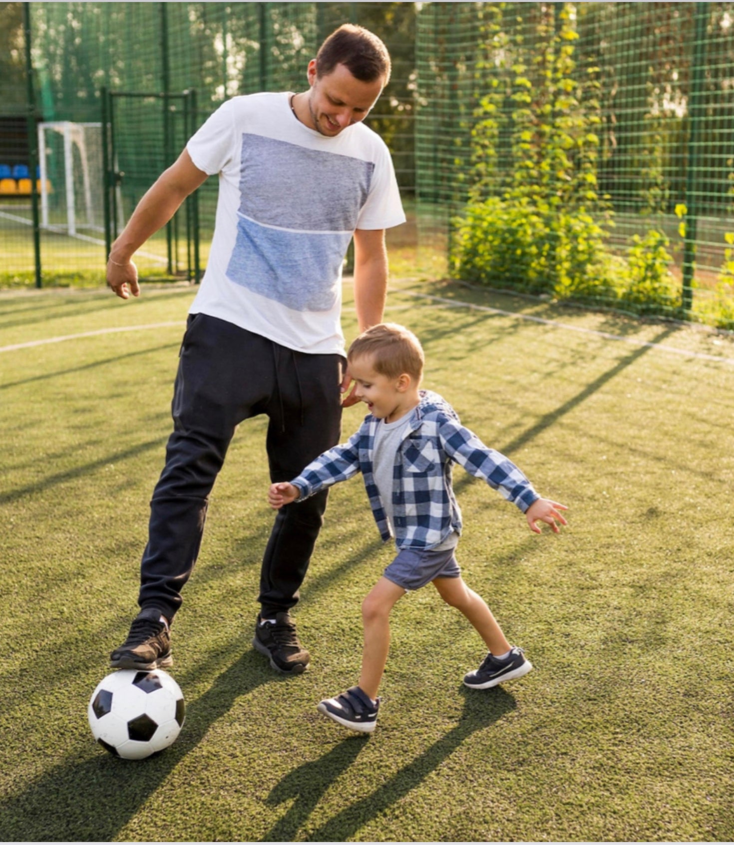 An adult and child enjoying a game of soccer together outdoors